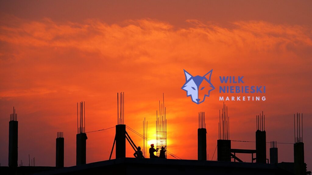 budowa na tle zachodzącego słońca a na tym logo agencji marketingowej w Warszawie - Wilk Niebieski