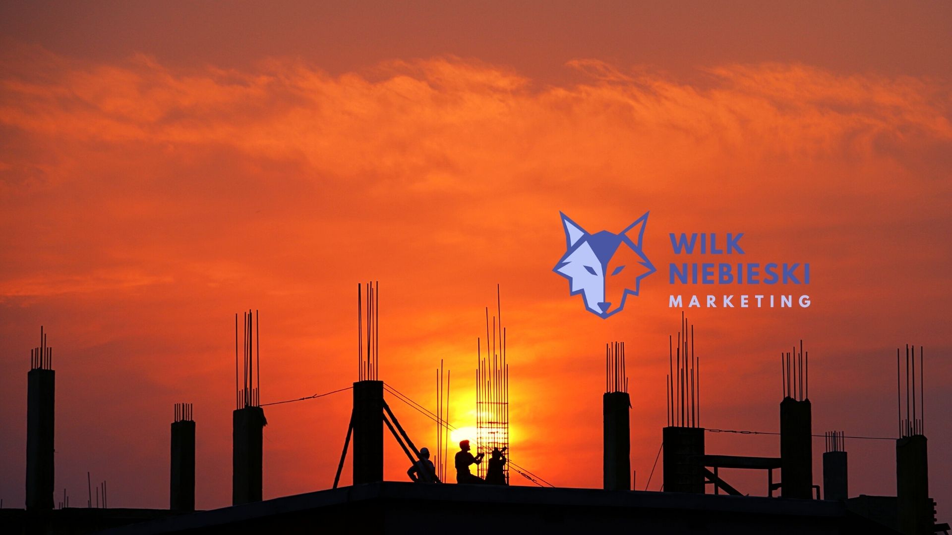 budowa na tle zachodzącego słońca a na tym logo agencji marketingowej w Warszawie - Wilk Niebieski